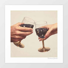 Load image into Gallery viewer, With “Primordial Wine,” the ordinary act of raising a glass is transformed into a spiritual and cosmic experience. Two hands hold golden wine glasses filled with galaxies instead of wine, symbolizing transcendence, spirituality, and the eternal passage of time. This surreal wall art print makes a perfect gift for wine lovers, spiritual seekers, or stargazers, and is an elegant choice for wineries, dining rooms, meditation corners, and homes embracing celestial decor.
